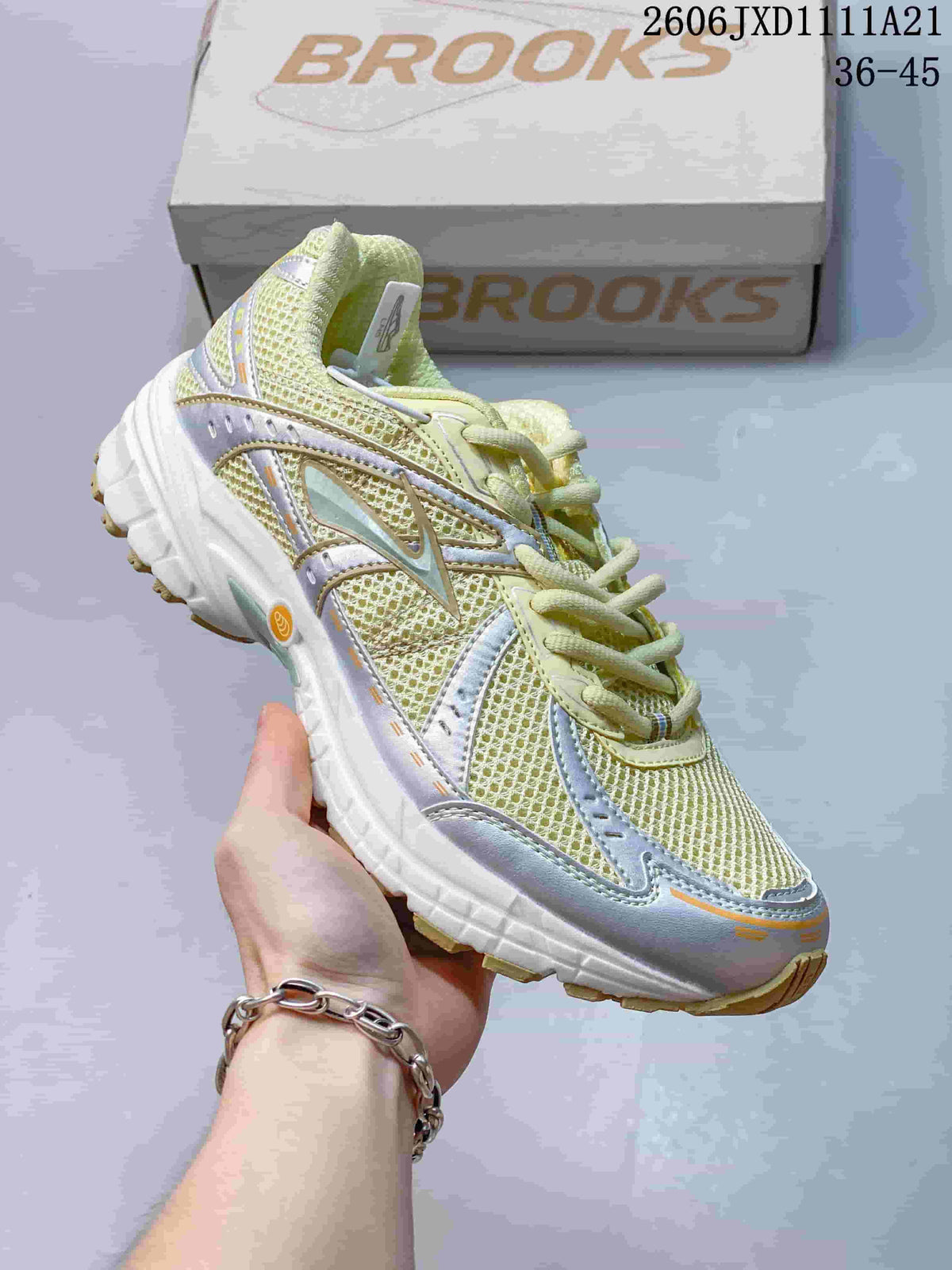Angled side view of a pale yellow and silver-toned Brooks sneaker