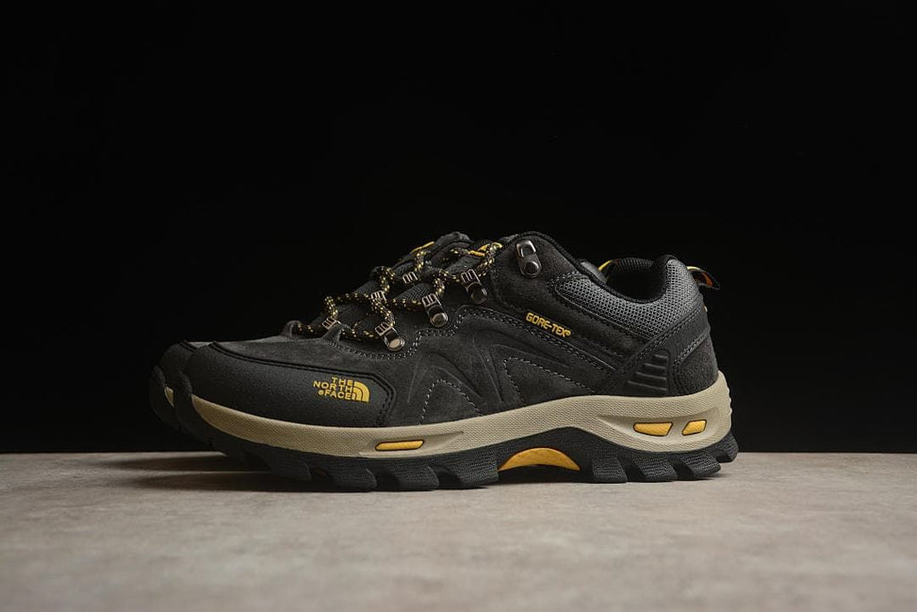 Side view highlighting the shoe's black upper, yellow branding and lugged outsole.