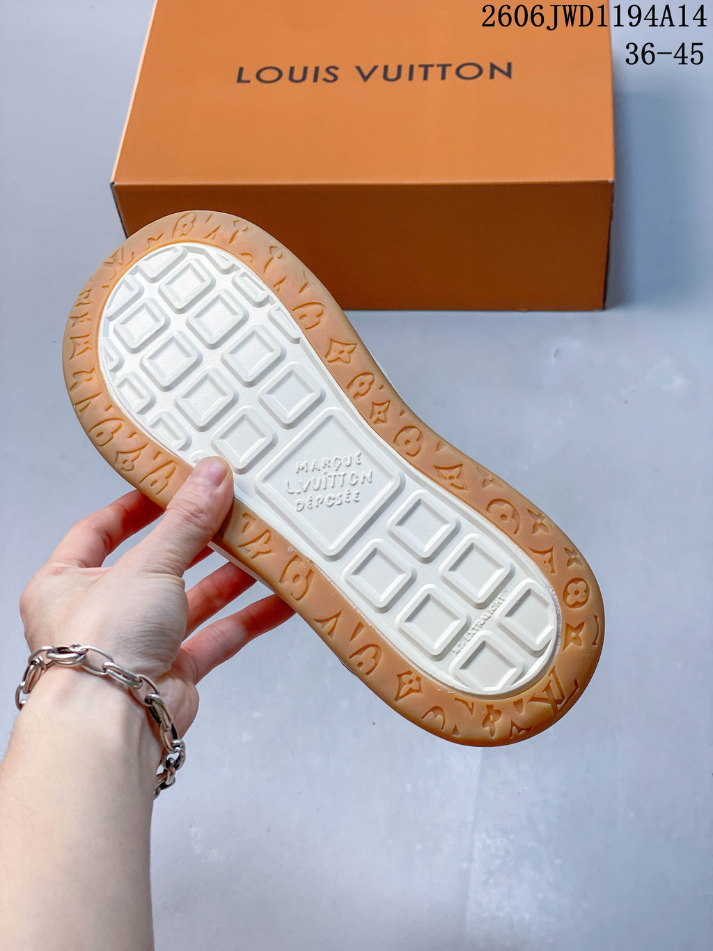 Underside of the sneaker showing a white tread center and tan outer sole with raised details.