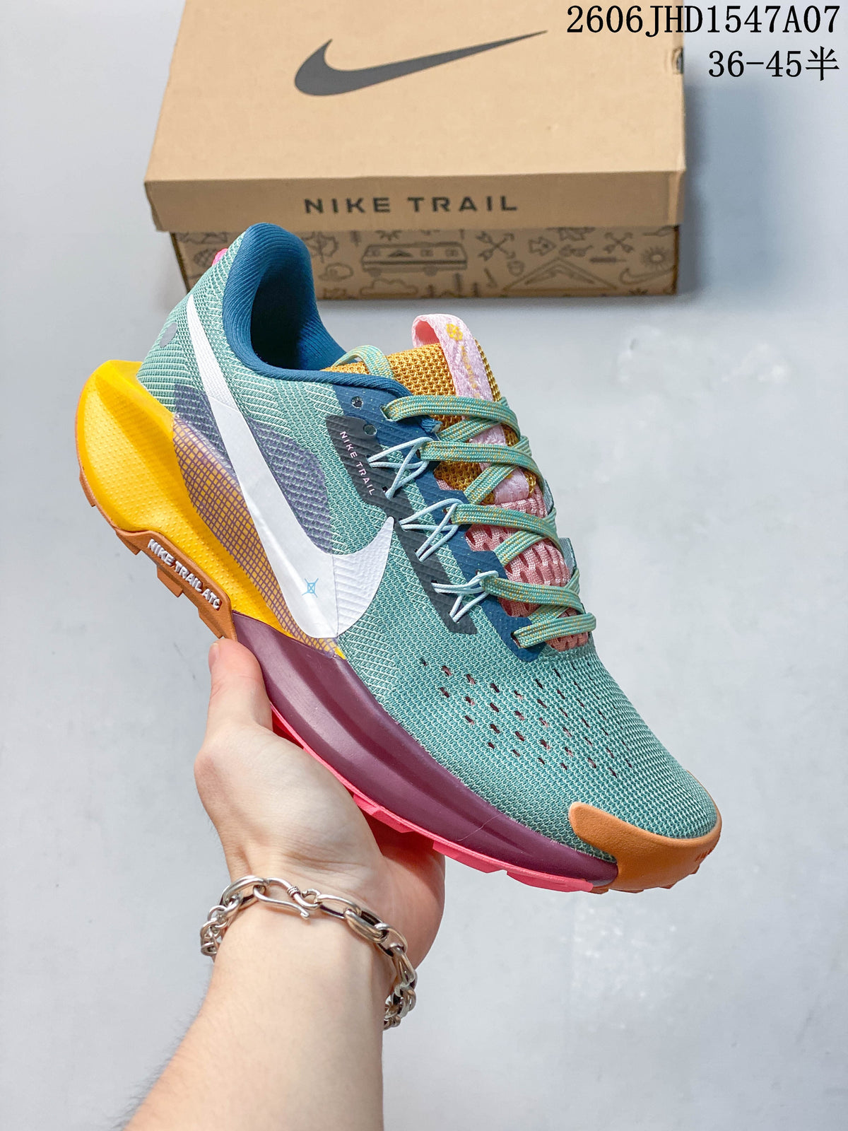 Angled side view of a teal Nike ReactX Pegasus Trail 5 shoe with a white Swoosh and multicolor outsole.
