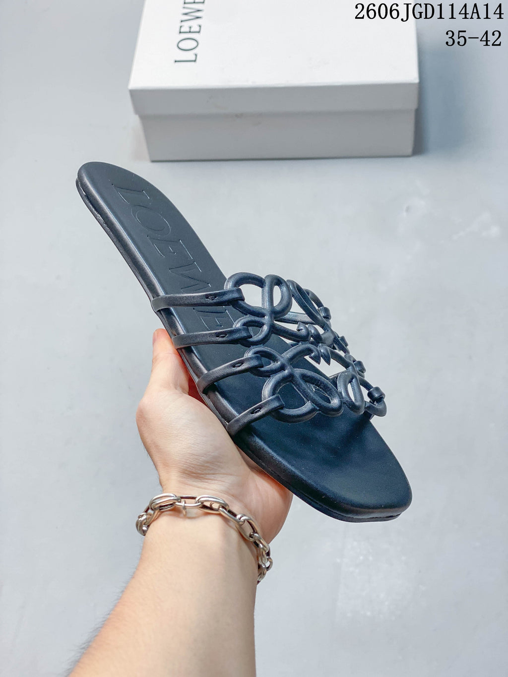 Angled close-up of a dark navy flat slide sandal showing its open toe and sculptural straps.