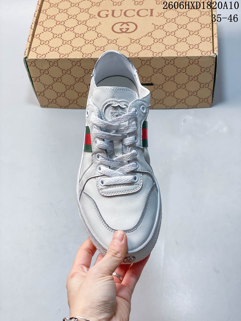 Front view of a white lace-up sneaker with stitched overlays and striped side details.
