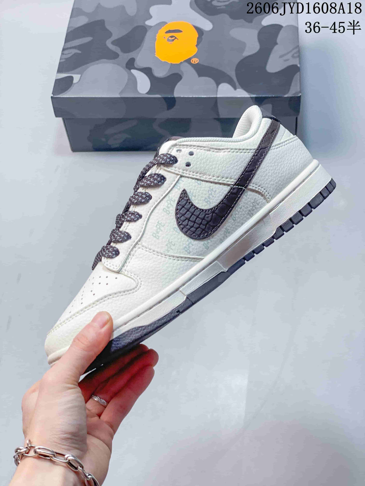 Side view of a cream low-top sneaker with a dark textured side accent and patterned laces