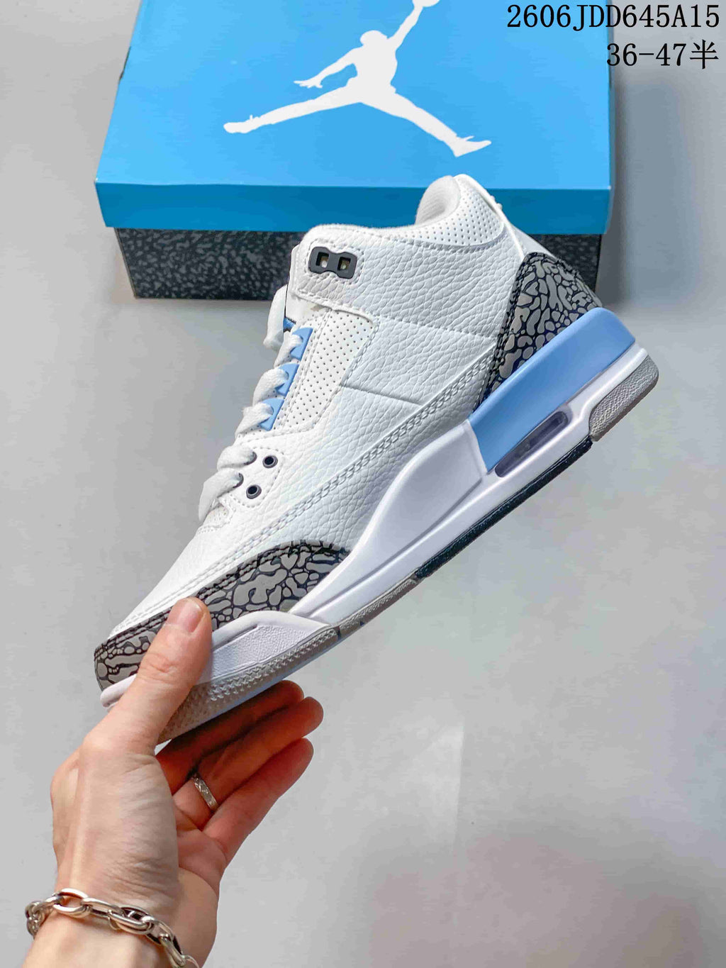 Side view of the white sneaker with blue accents and elephant-print overlays.