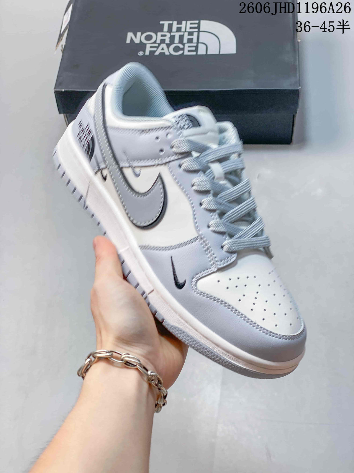 Close view of a light gray and white low-top sneaker with perforated toe and dark outlined swoosh.