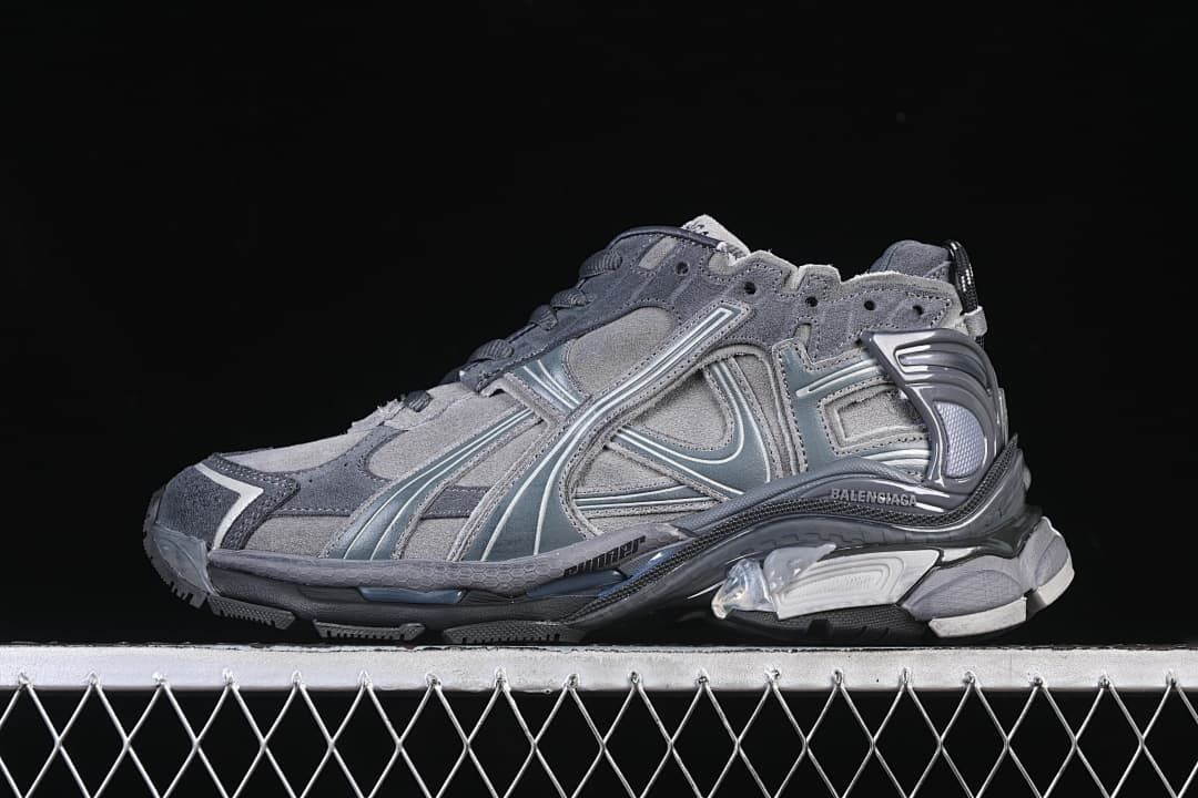 Side profile of a grey Balenciaga Runner-style sneaker against a dark background