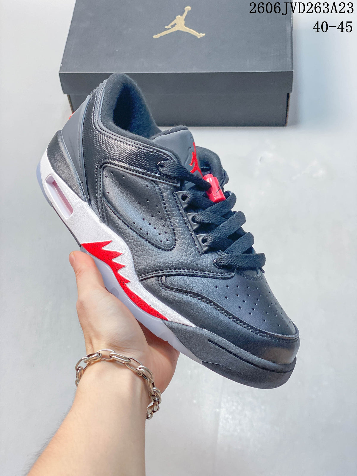 Side view of the dark gray low-top shoe with red and white details.