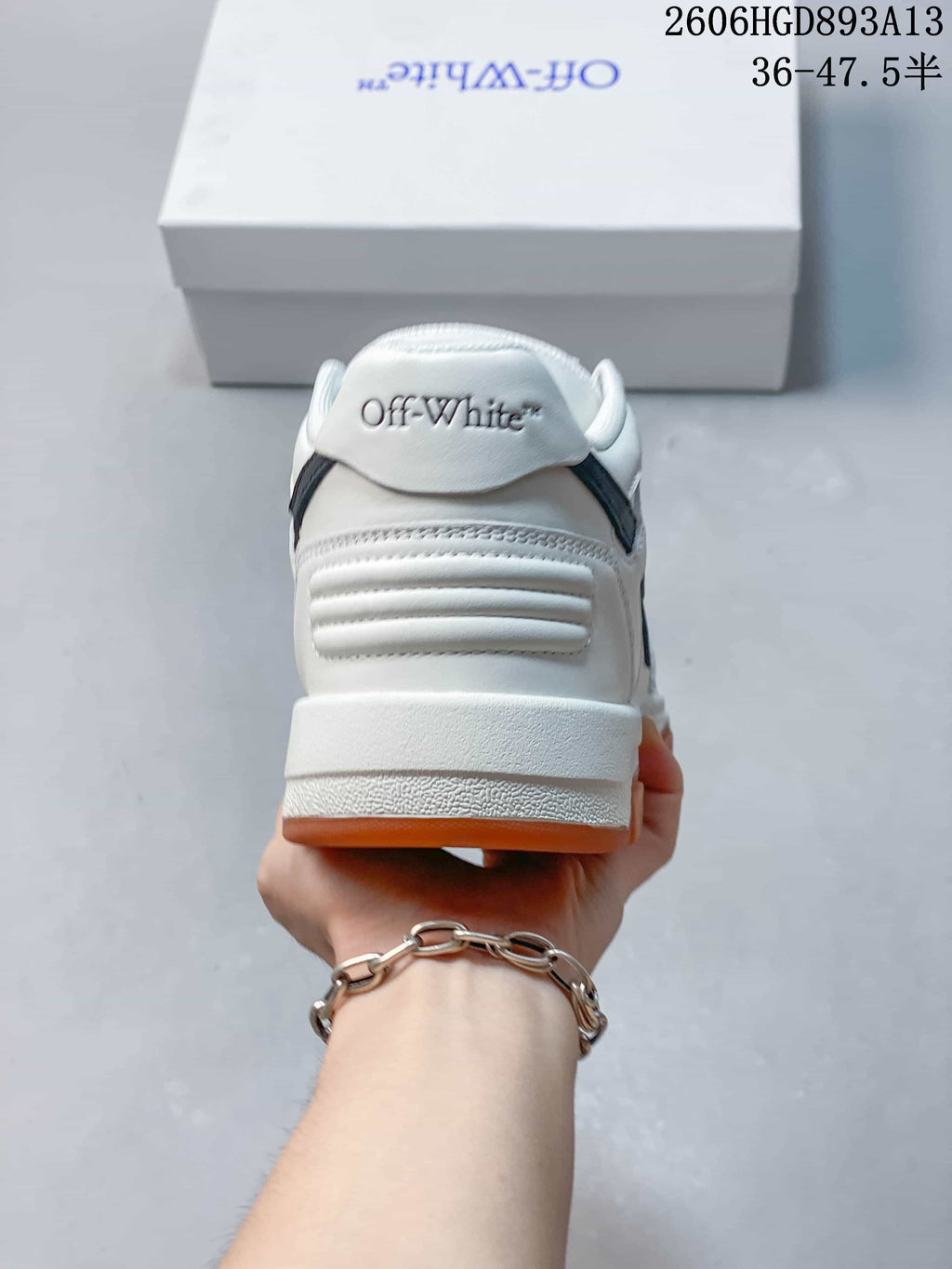 Rear view of the white low-top sneakers, showing the heel and black accents.