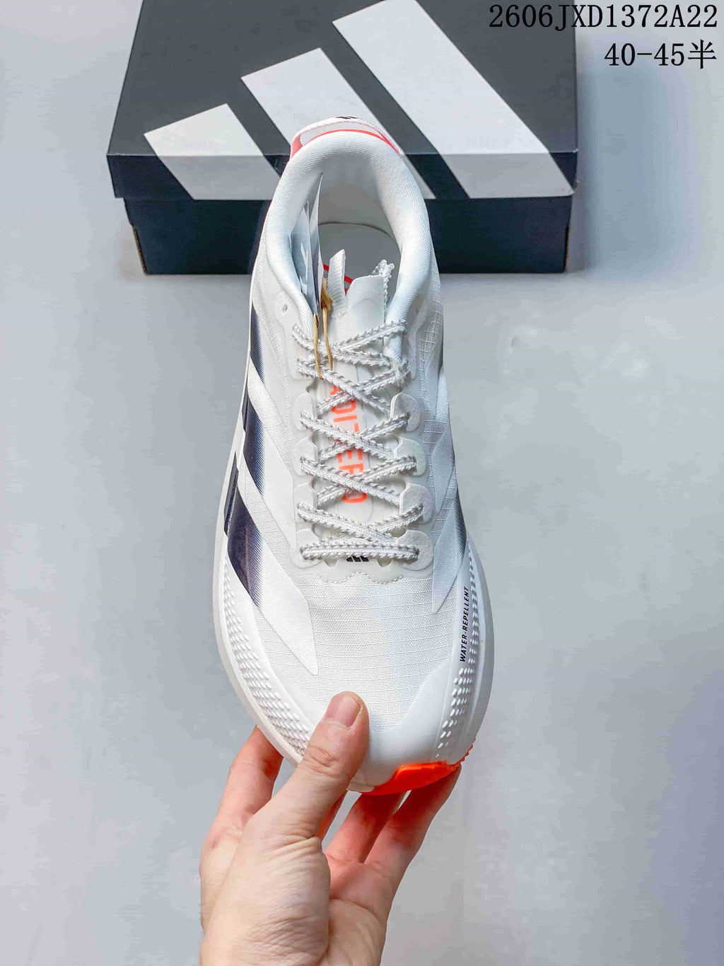 Top view of a white lace-up running shoe with dark side stripes and orange details.