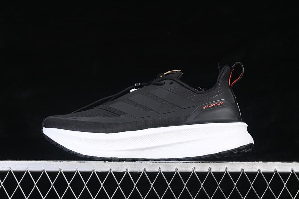 Side view of a black adidas Ultraboost 5 shoe with a white midsole and red heel detail.