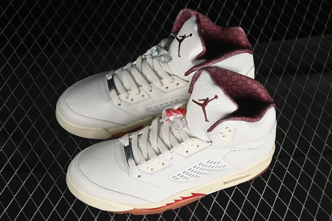 Pair of light-colored Air Jordan 5 sneakers with burgundy accents
