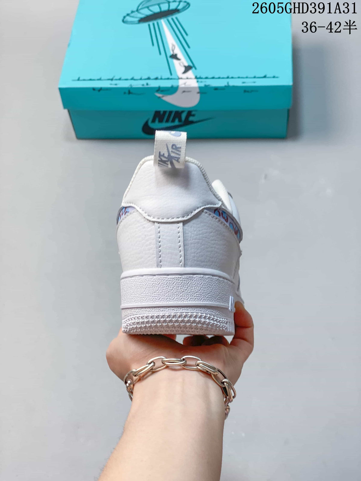 Rear view of a white low-top sneaker with patterned side-panel trim and a turquoise shoebox behind it