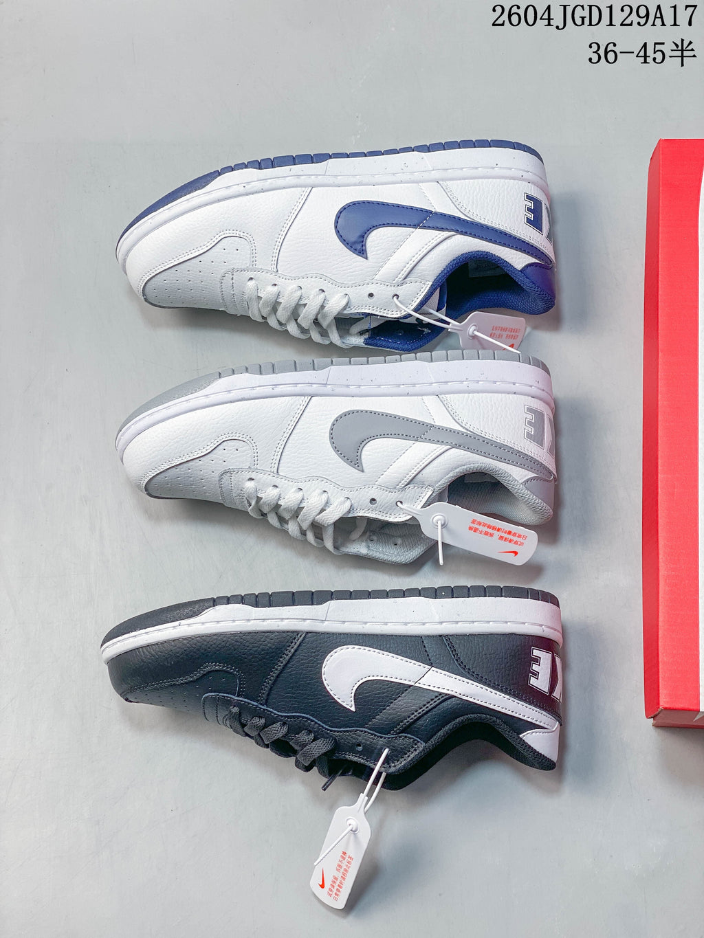 Three Nike Big Low low-top colorways shown from the side: white with blue accents, white with gray accents, and dark navy with white accents.