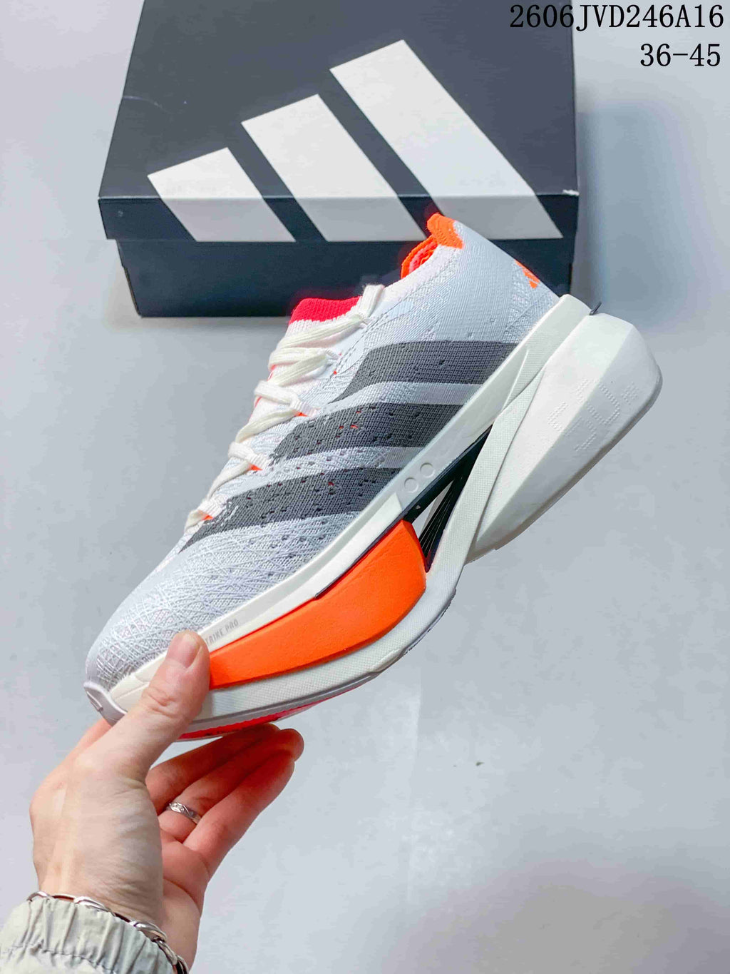 Side view of the shoe showing dark stripes and a bright orange sole accent.