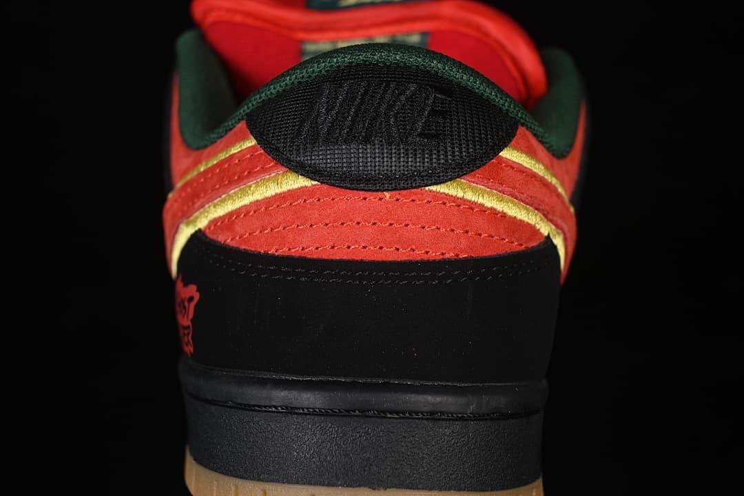 Rear view highlighting the red-orange heel panels, yellow trim, dark green collar, and black heel panel.