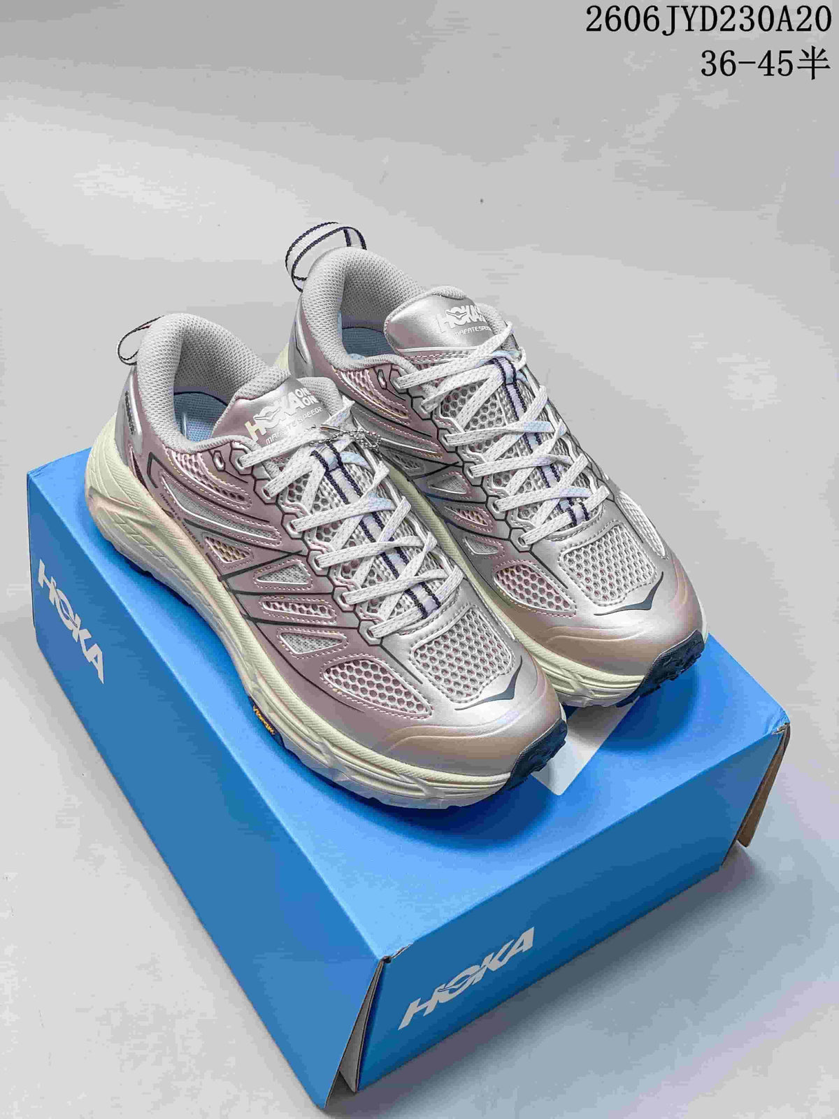 Pair of silver-toned Hoka One One running shoes on a blue shoe box