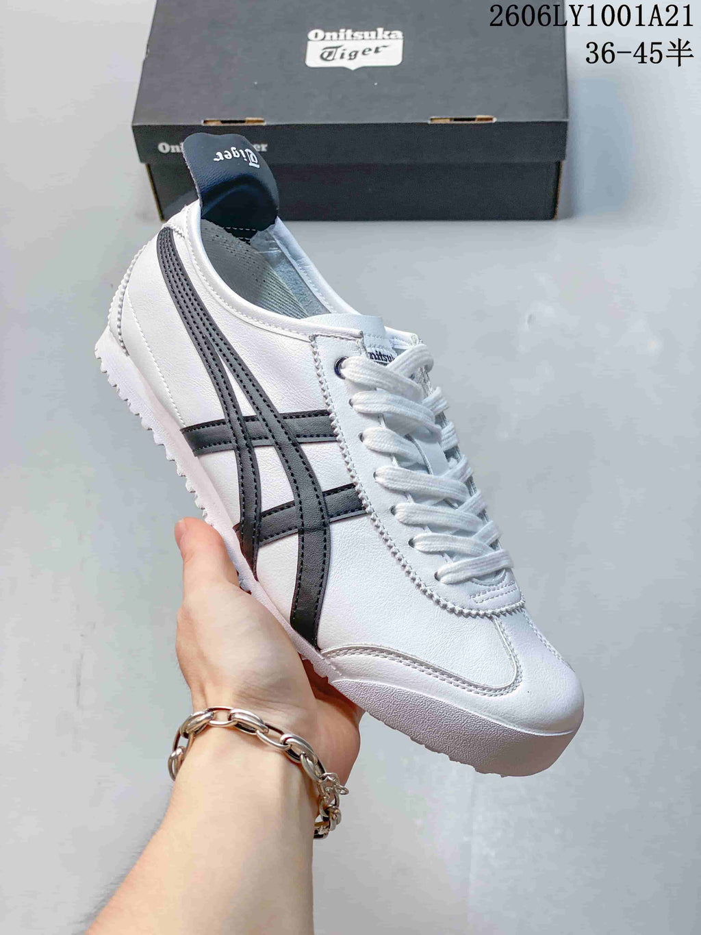 Angled side view of a white Onitsuka Tiger sneaker with dark navy stripes