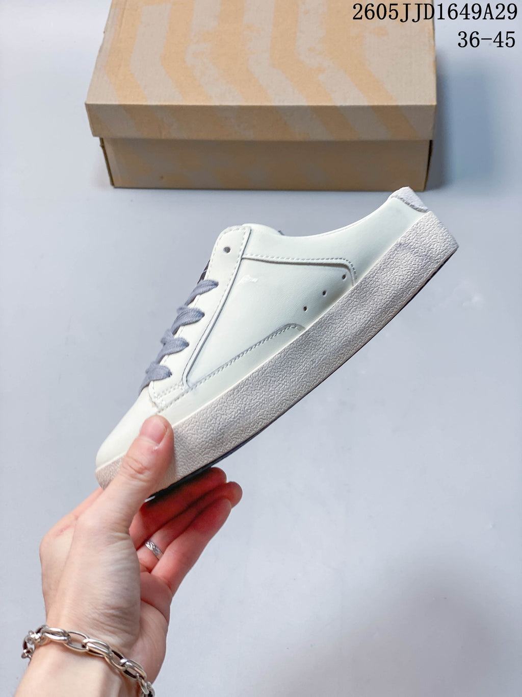 Side view of a white backless sneaker with gray laces and a textured sole