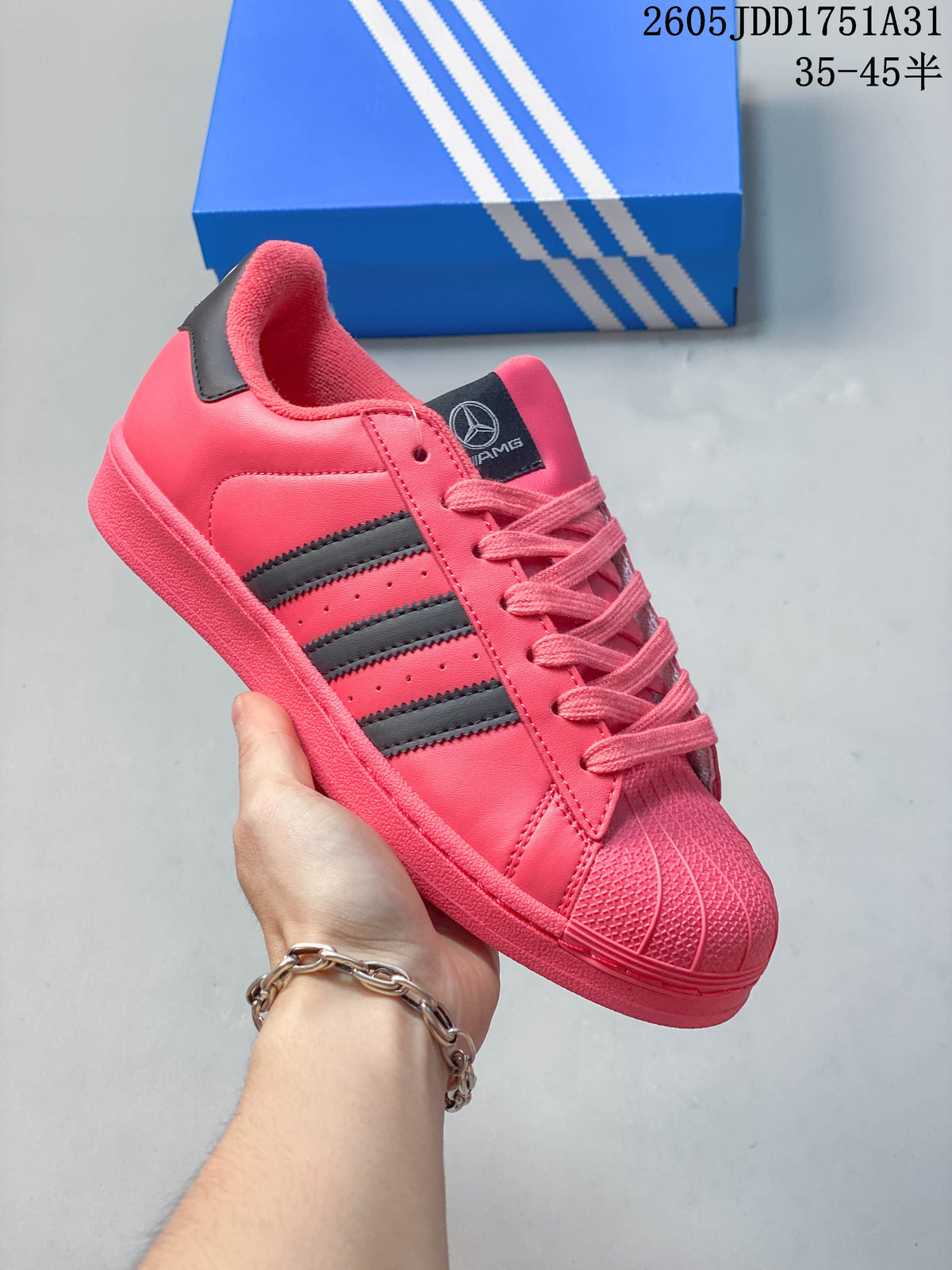 Bright pink sneaker with dark stripes and a shell toe