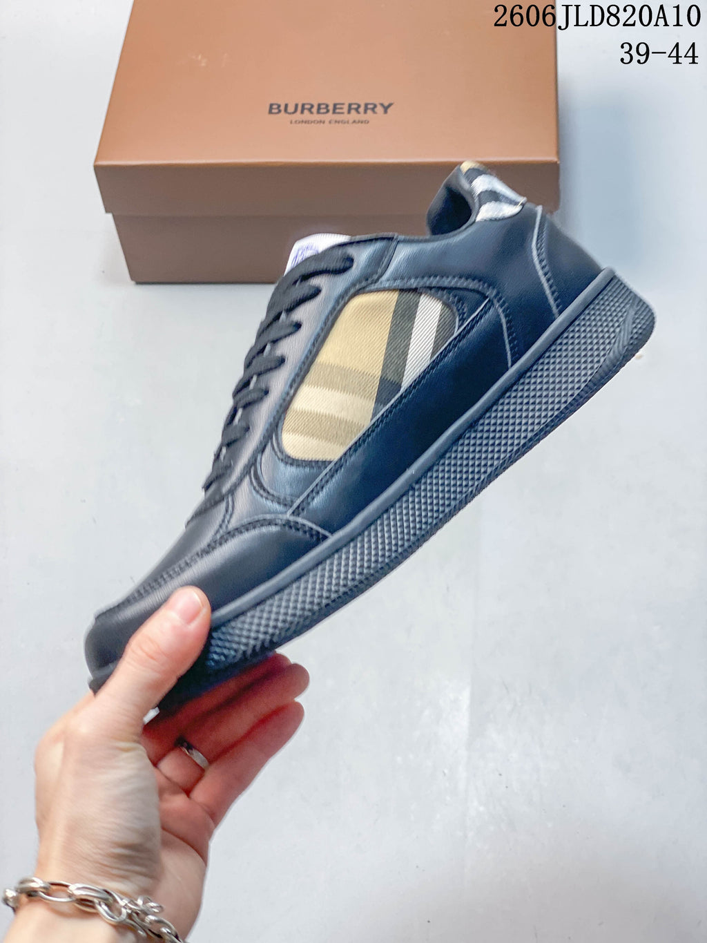 Side view of a navy lace-up sneaker with beige check-pattern side panel and textured outsole