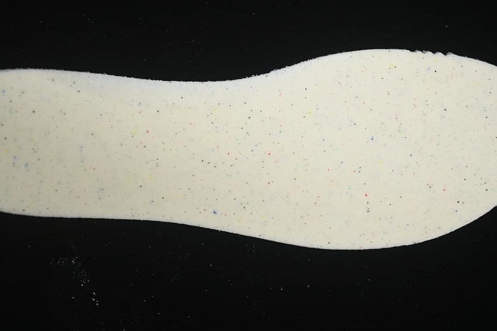 Close-up of a light-colored shoe insert with multicolor speckles.