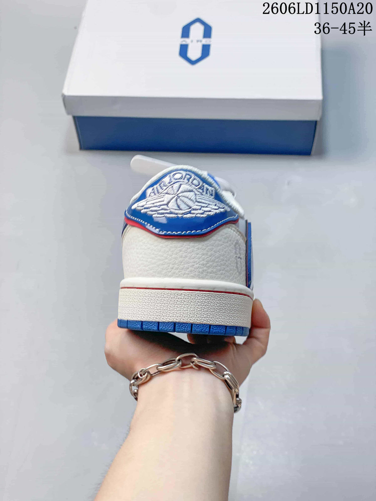Rear view of a white sneaker with a blue heel tab and blue outsole.