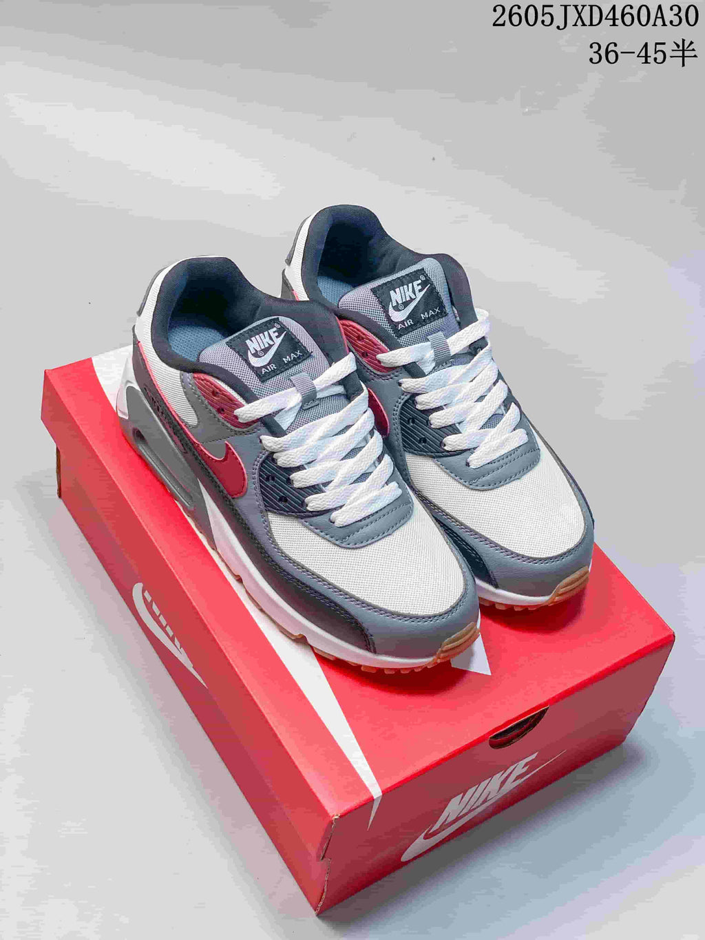 Pair of grey, white, and red Nike Air Max 90 sneakers on a red shoebox; image overlay shows sizes 36–45.5.