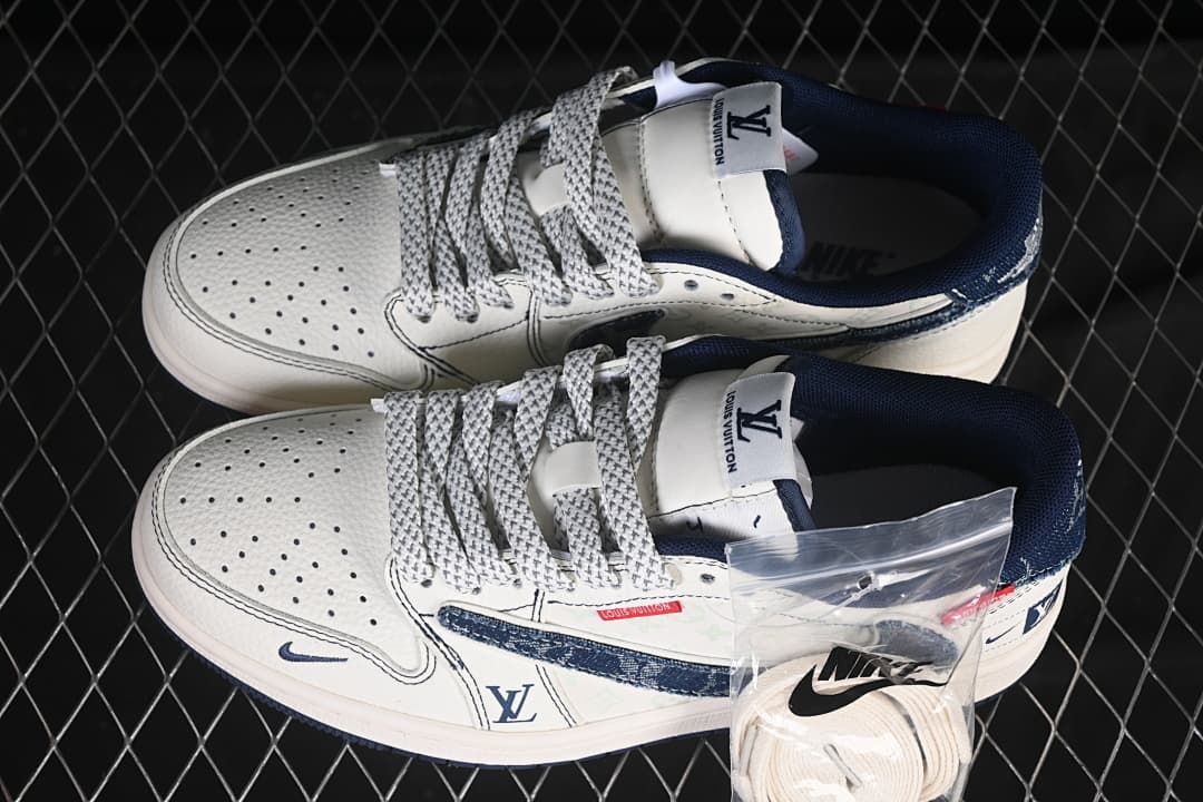 Overhead view of a pair of white and navy low-top sneakers with contrast laces and spare laces in a bag