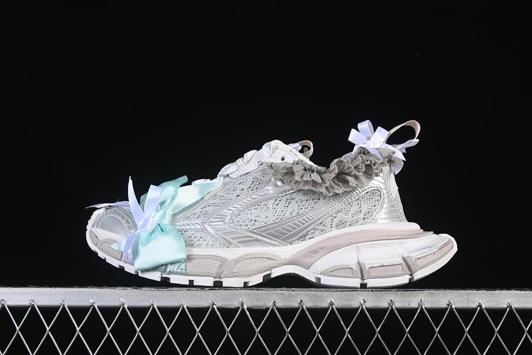 Side view of light silver Balenciaga 3XL sneakers with pale aqua bows and gray ruffle trim