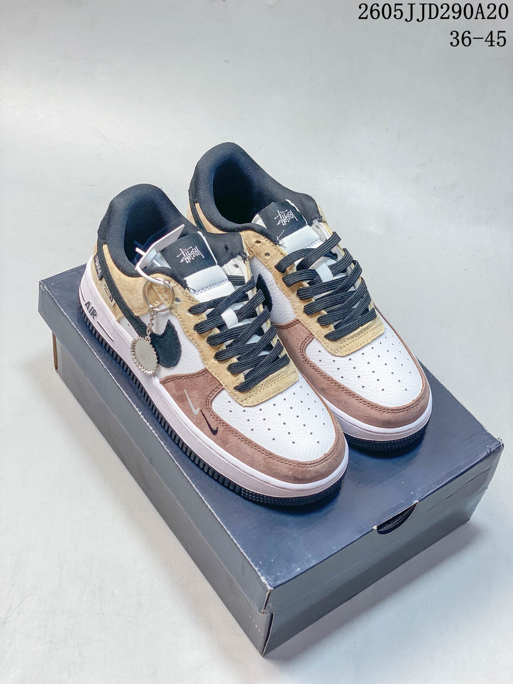 Pair of layered Nike Air Force 1 Shadow sneakers in white, beige, brown, and black, shown on a shoebox