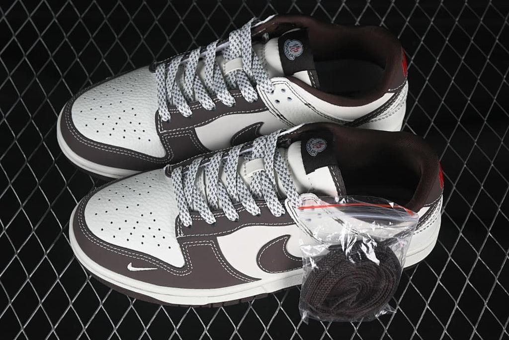 Pair of cream and brown low-top sneakers with patterned laces and a spare pair of dark laces