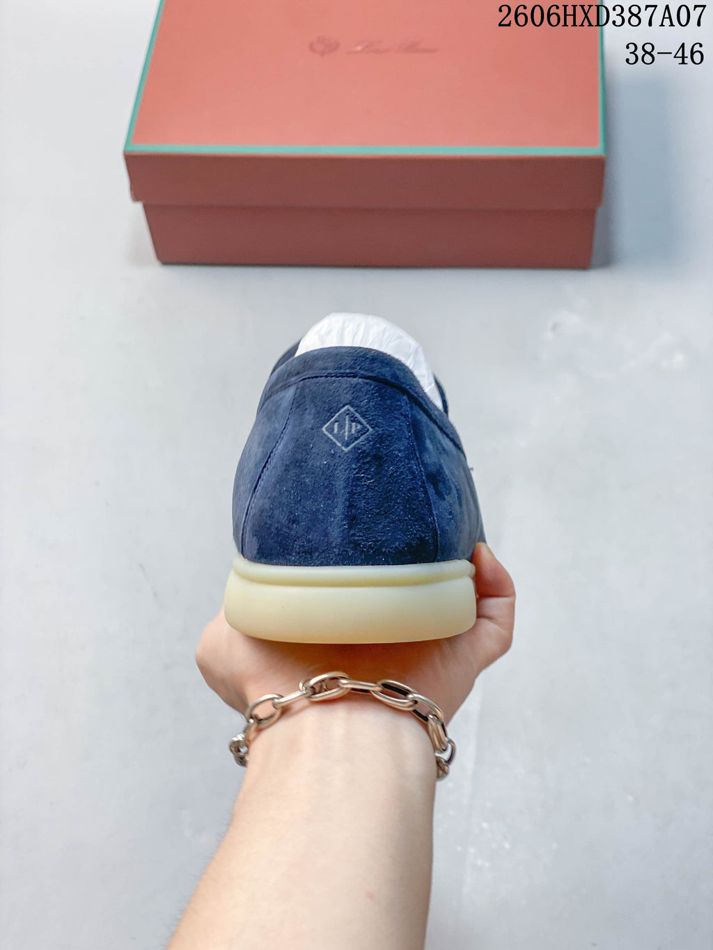 Rear view of a blue loafer with a small heel emblem and light-colored sole.