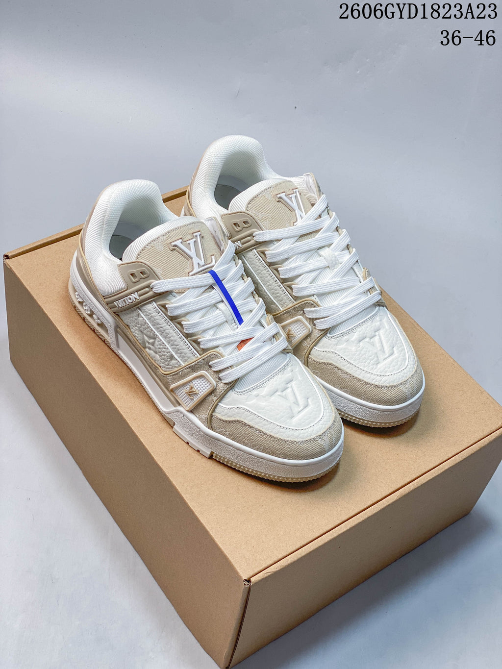 Pair of white and beige Louis Vuitton Trainer Low sneakers on a brown box