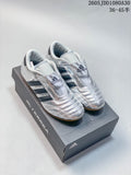 Pair of reflective silver Adidas Taekwondo shoes with dark stripes and gum-colored soles