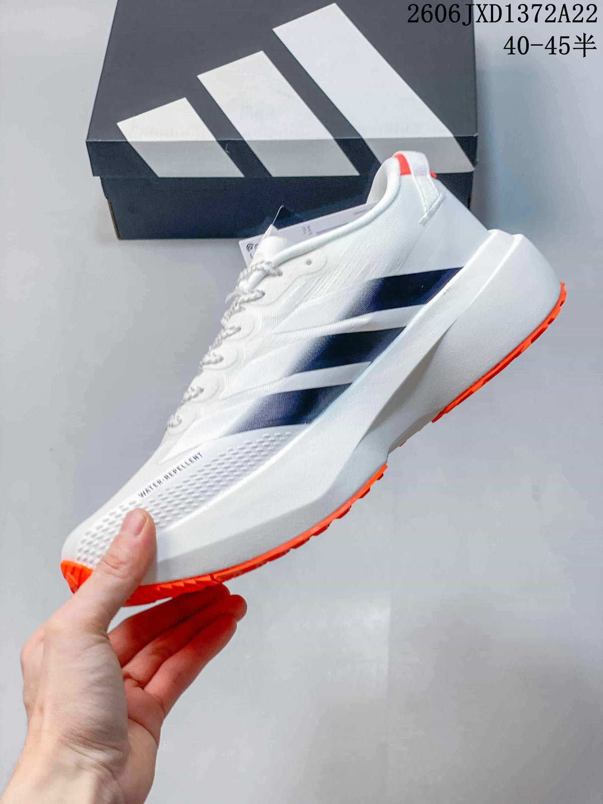Side view of a white Adidas Adizero Evo SL ATR shoe with dark stripes and orange outsole accents.