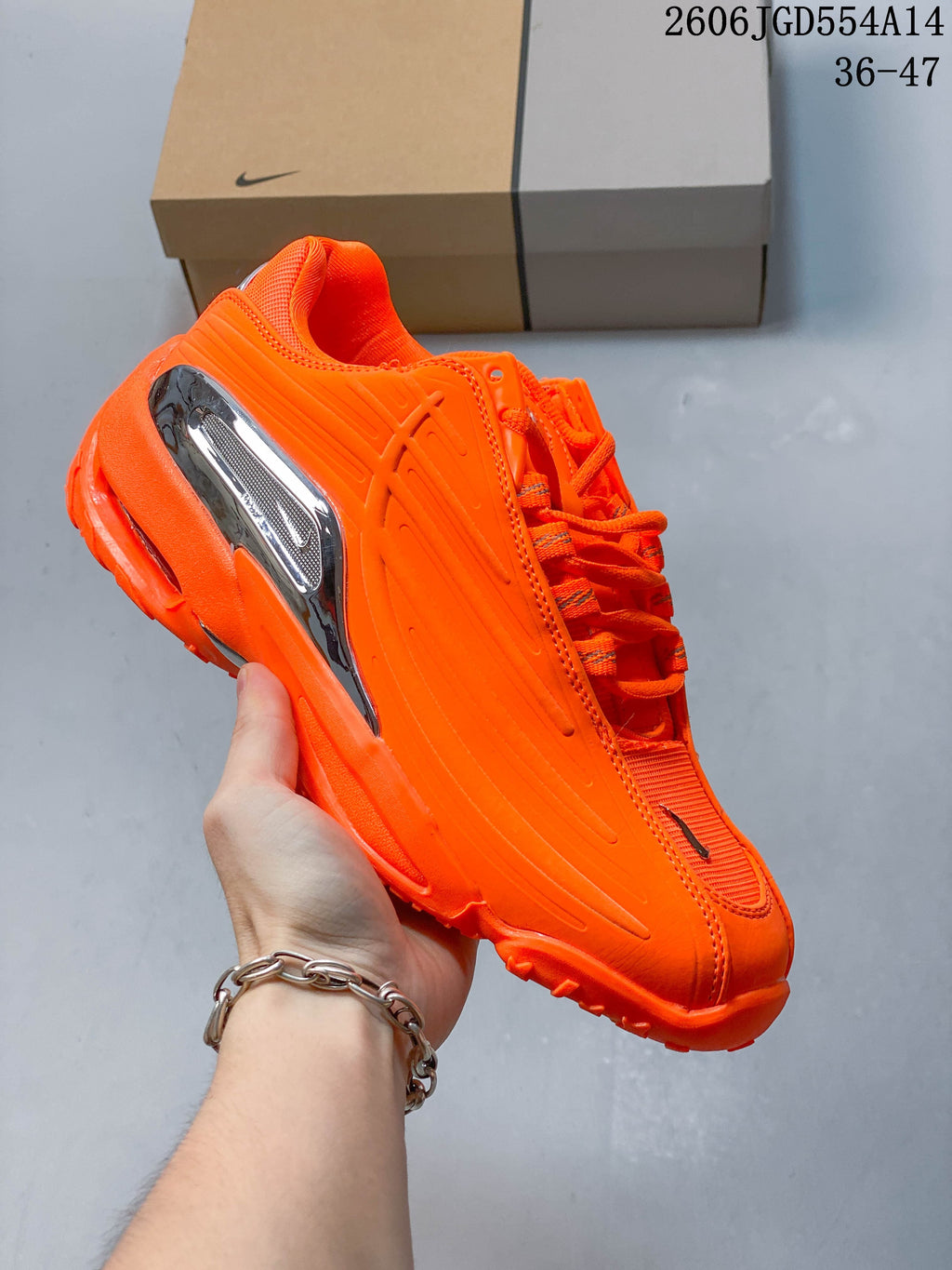 Opposite side profile of the orange sneaker with reflective silver heel detail