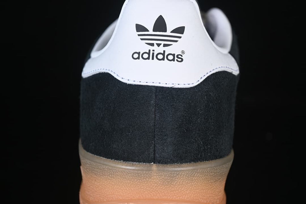 Rear view of the black heel panel, white heel tab, and gum-colored sole.
