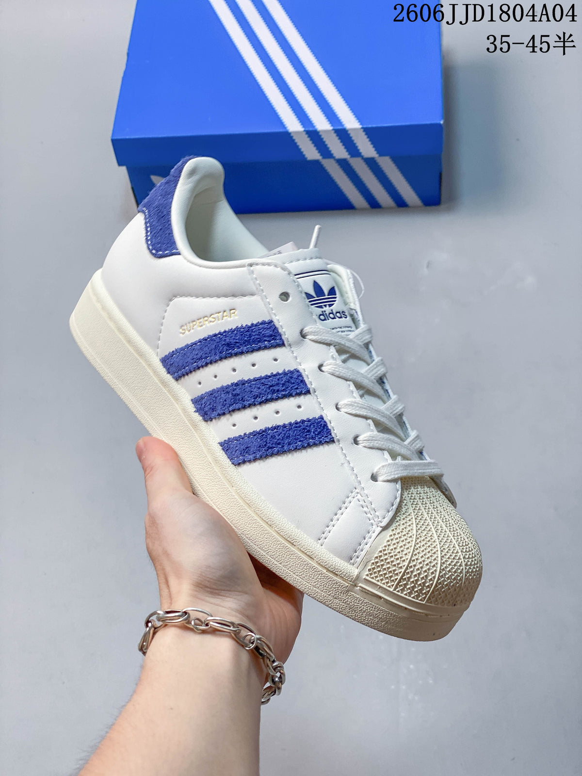 Close view of a white sneaker with blue side stripes, padded collar, and shell-style toe.