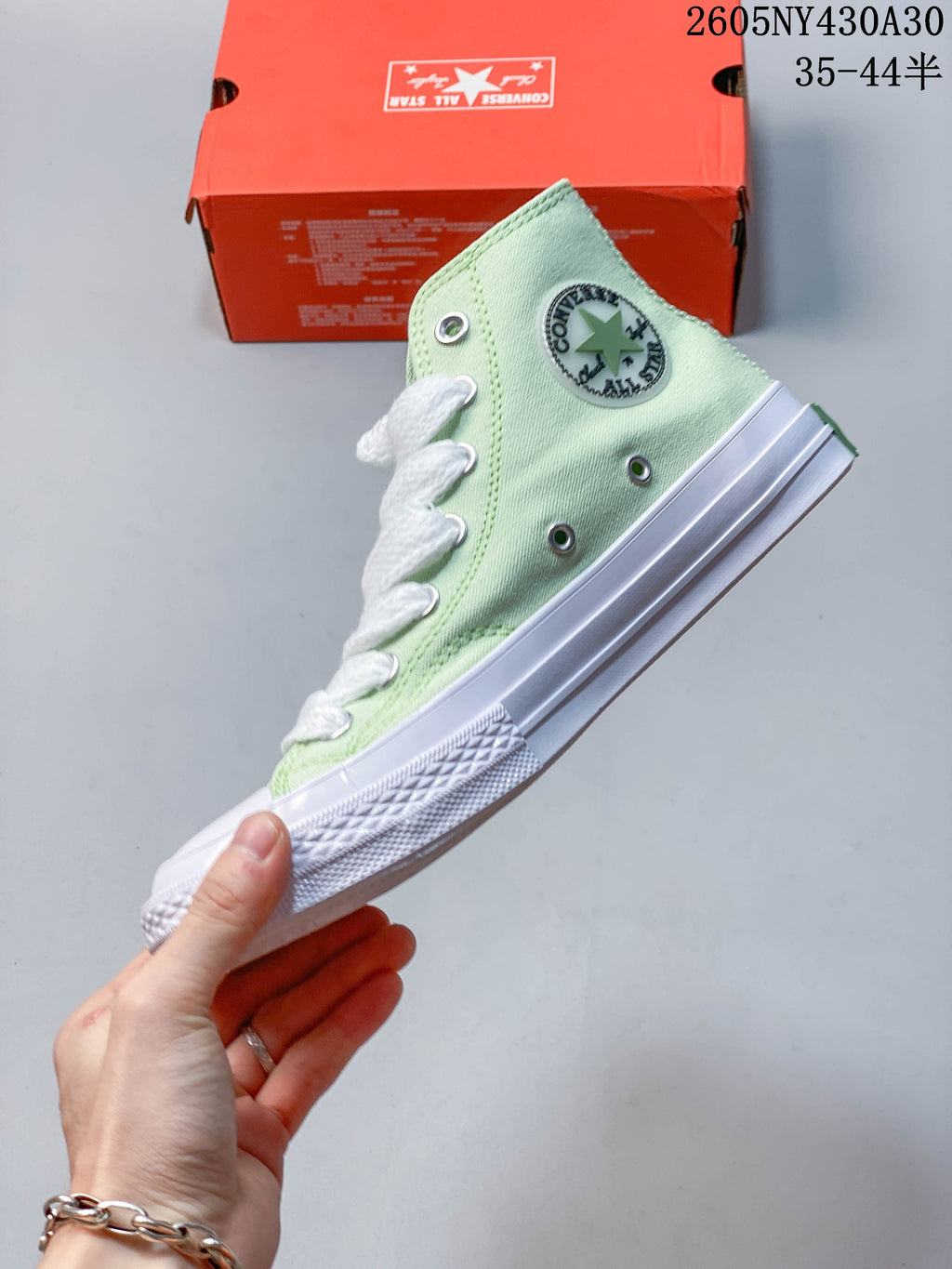 Side view of a pale mint green high-top sneaker with white laces and a rubber sole