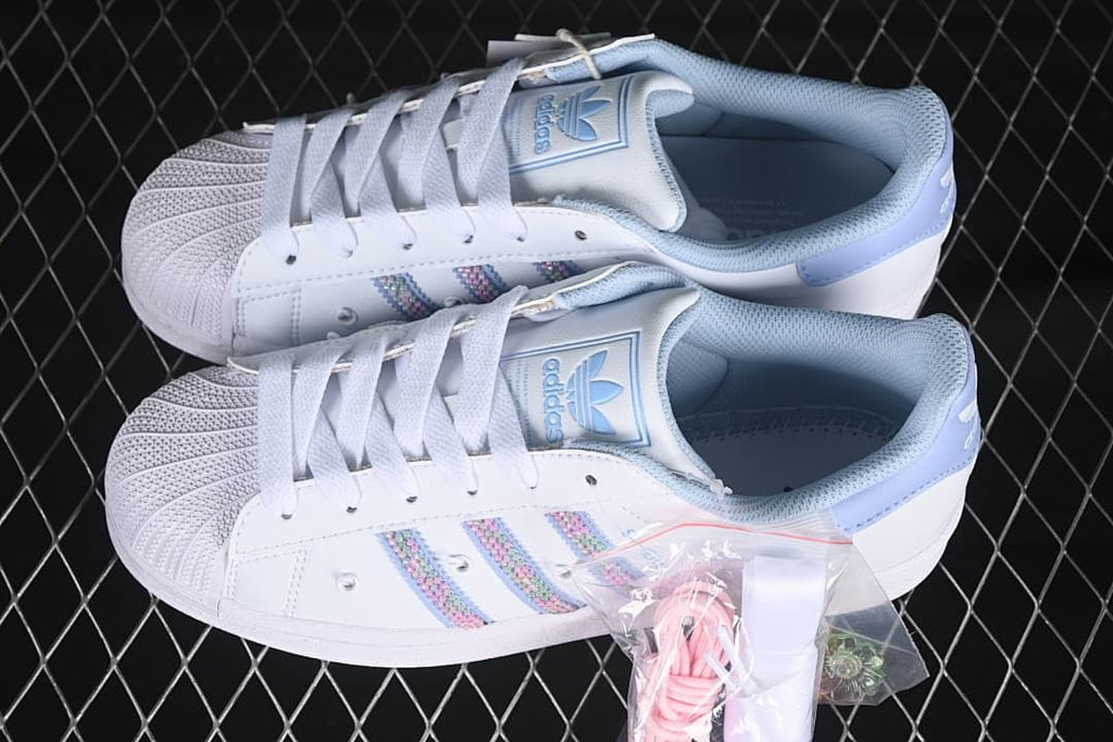 Pair of white Superstar II sneakers with pastel stripes and additional lace accessories pictured