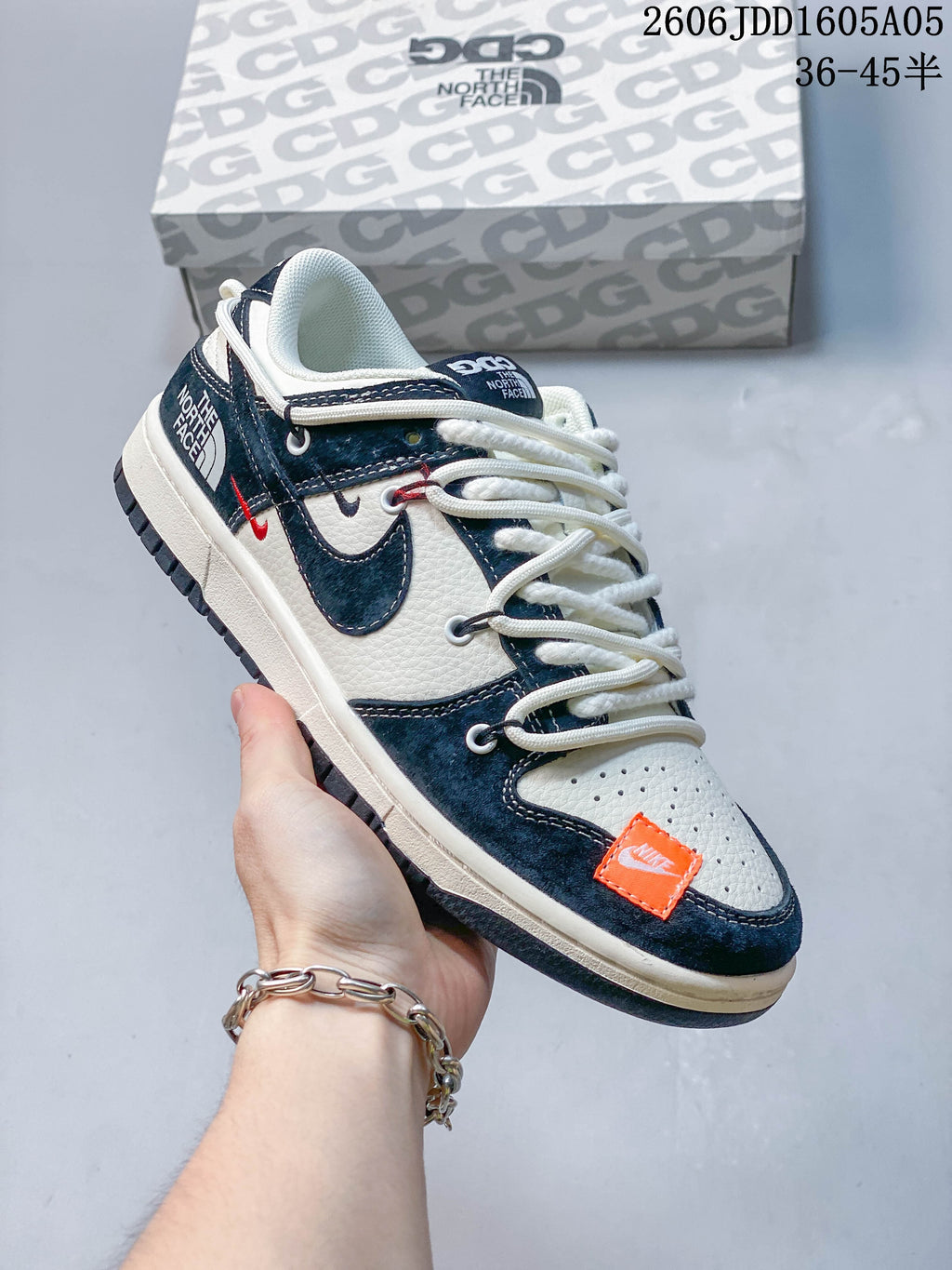 Navy and off-white low-top sneaker with contrasting panels, rope-style laces and a branded box.