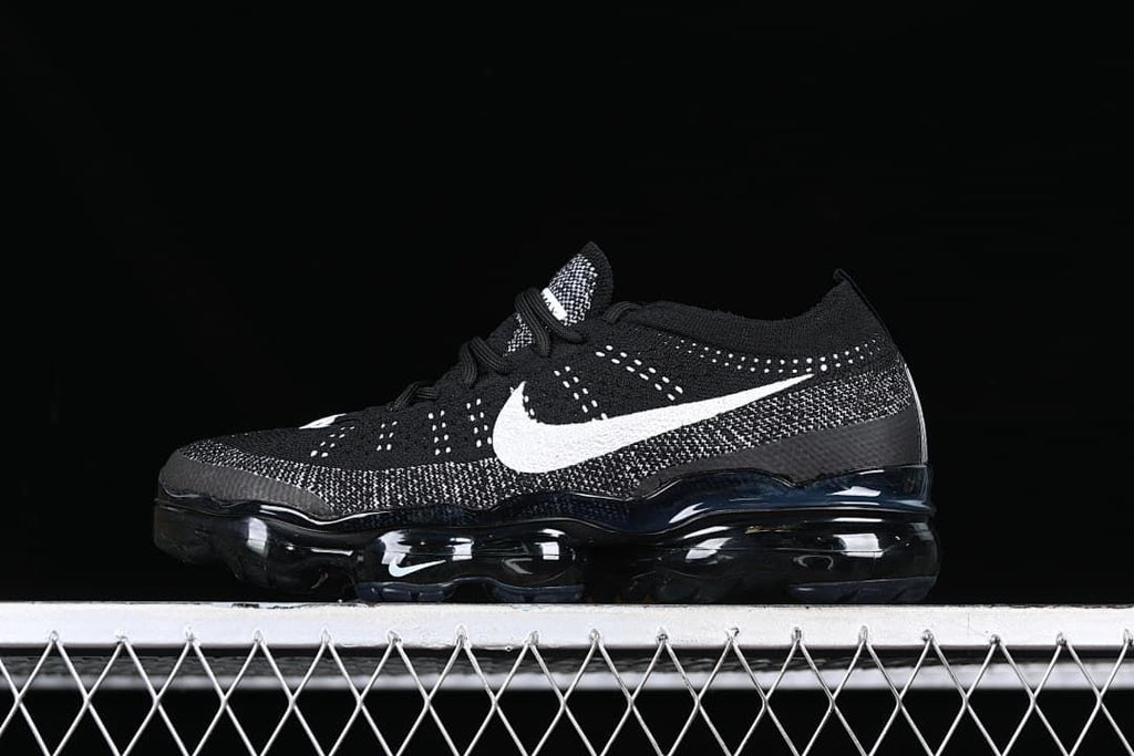 Side view of a black Nike Air Vapormax 2023 Flyknit with white Swoosh and visible air-cushioned sole