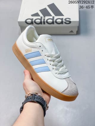 Angled side view of the white sneaker with light blue stripes, gray toe detailing, and gum-colored sole.