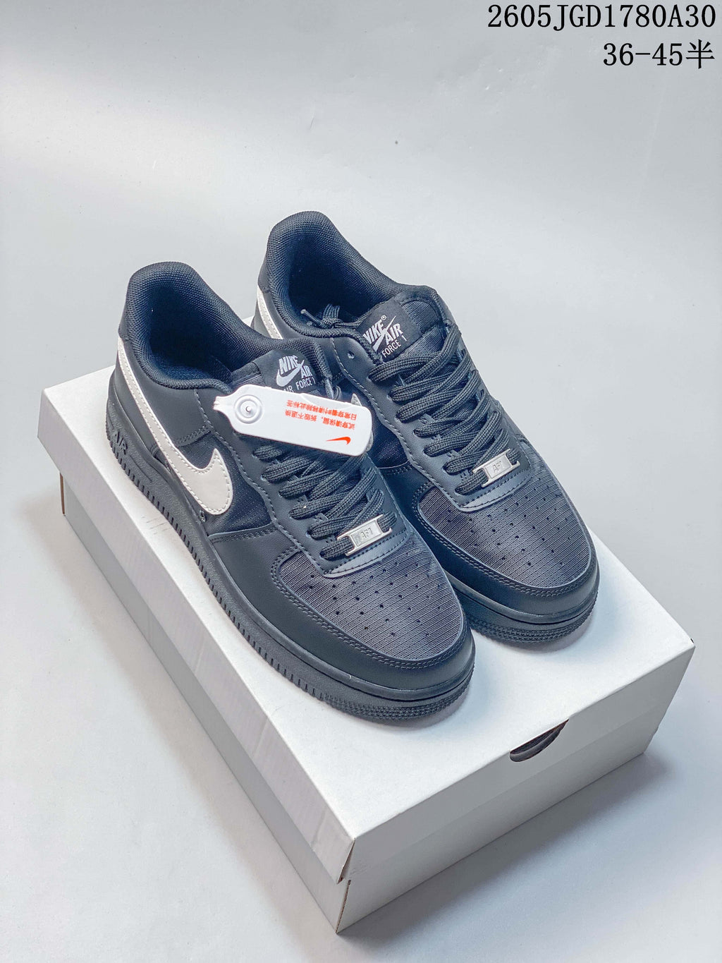 Pair of dark gray Nike Air Force 1 Low sneakers with light-colored Swooshes, shown on a box.