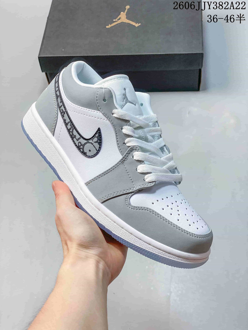 White and gray low-top sneaker with a patterned gray Swoosh and pale blue outsole.