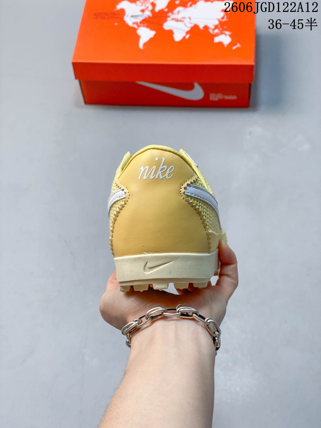 Heel view of a pale yellow Nike Astro Grabber sneaker with white branding and an off-white sole.