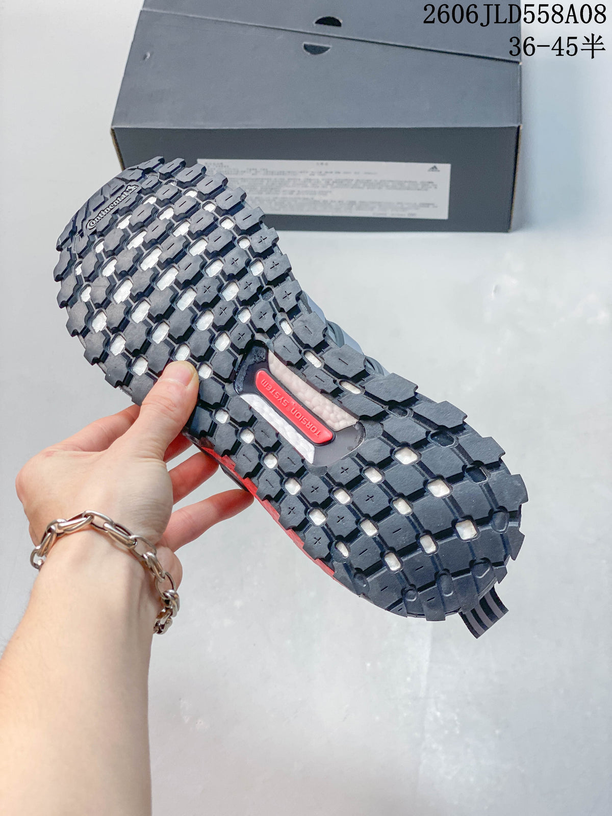 Close-up of the sneaker outsole showing a deep, block-pattern tread and a red central detail.