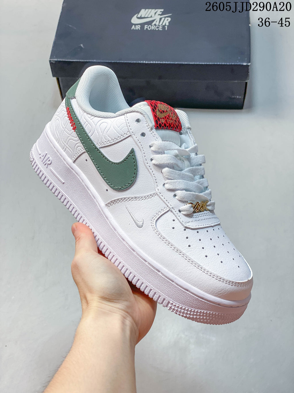 Angled side view of a white sneaker with green side accent, patterned heel panel, and red tongue detail.