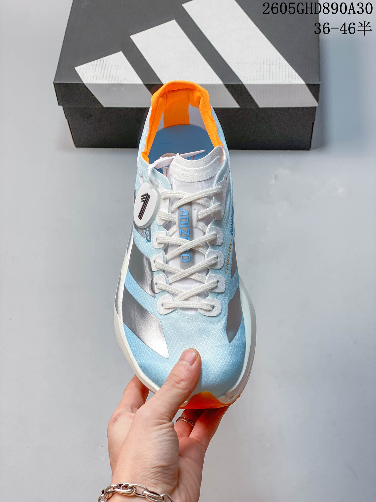 Front view of the shoe showing white laces and a pale blue upper