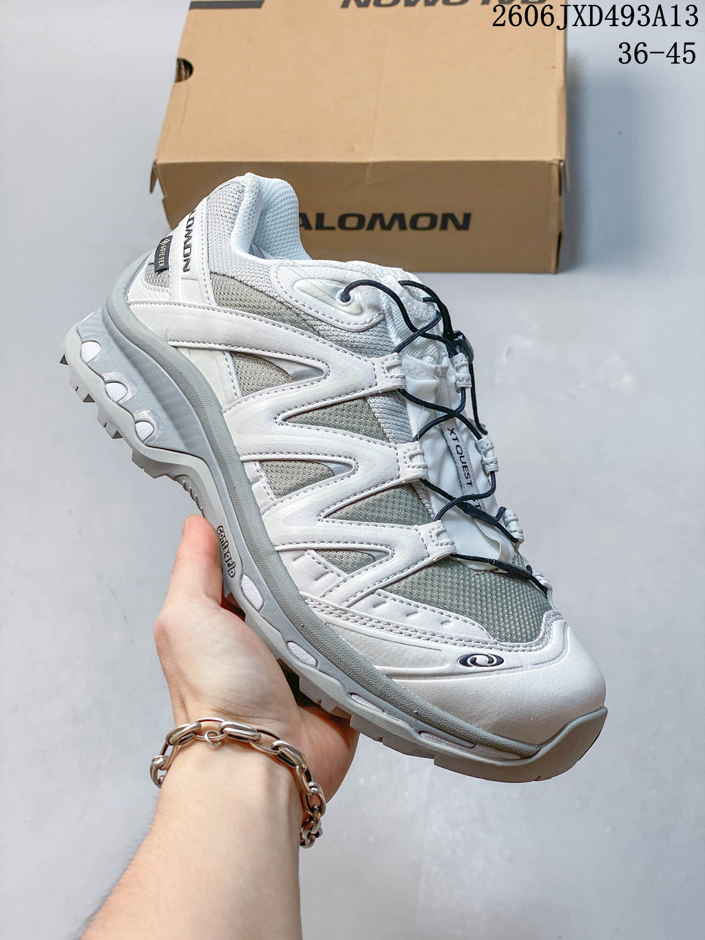 Angled side view of the white and grey sneaker with a treaded outsole.